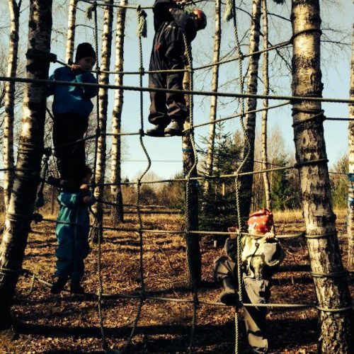 Barn fra Solbakken Barnehagen som klatrer i et nett mellom 2 trær. Foto