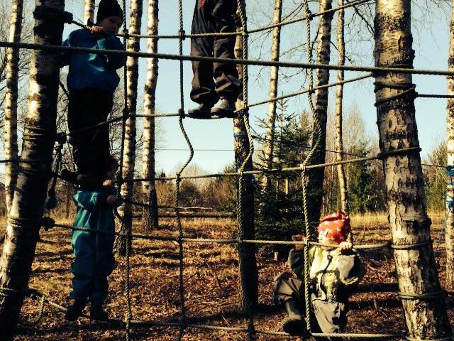 Barn fra Solbakken Barnehagen som klatrer i et nett mellom 2 trær. Foto